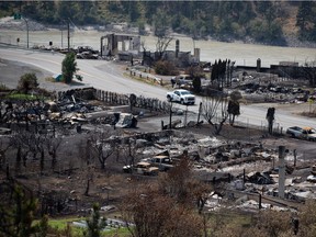 An RCMP vehicle drives past the remains of vehicles and structures in Lytton on July 9, 2021, after a wildfire destroyed most of the village on June 30.