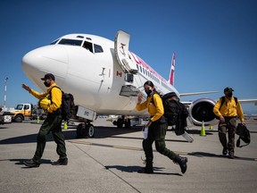 Firefighters from Mexico walk across the aircraft parking area after arriving on a charter flight in Abbotsford on Saturday, July 24, 2021. Firefighters will assist B.C. as the province deals with hundreds of wildfires burning in the province. They will undergo rapid COVID-19 testing and then be deployed to the Interior where they will stay in several bubbles separate from the more than 3,000 firefighters already working.