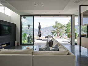 A dropped ceiling and large fireplace mantel define the living room. Opposite, a built-in credenza, custom-configured by interior designer Marlene Bourque, divides off the dining area and doubles as a wired stereo cabinet, which housed the original owner's turntable and vinyl collection.