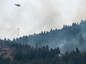 Water is dropped from the bucket of a helicopter onto a hotspot of the Mount Law wildfire near Peachland, British Columbia, Canada August 16, 2021.