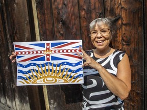 Lou-Ann Neel at the Royal B.C. Museum Thunderbird Park with a print of a new B.C. flag she has designed with coastal First Nations elements.
