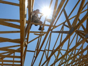 A construction worker ties roof trusses together at a condominium project in Port Stanley, Ont.