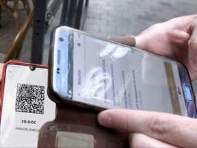 A waiter checks a customer's COVID-19 health pass on a mobile phone at the entrance of his cafe in Valenciennes, France, Aug. 9, 2021.