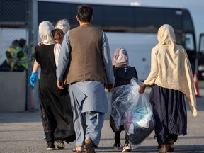Afghan refugees head for buses after arriving at Toronto Pearson International Airport.