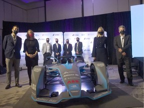 Dignitaries and officials gather around a race car after the announcement of the Canadian E-Fest program at the Douglas Hotel in Vancouver on Sept. 29, 2021.