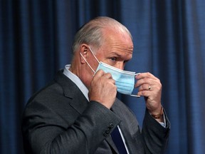 Premier John Horgan puts on his mask following a press conference to update on the province's fall pandemic preparedness plan from the press theatre at Legislature in Victoria, Wednesday, Sept. 9, 2020.