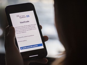 A woman looks at the Quebec government's new vaccine passport on a smart phone.