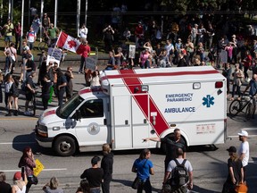 An ambulance passes through a crowd of people protesting COVID-19 vaccine passports and mandatory vaccinations for health care workers, in Vancouver, on Wednesday, Sept. 1, 2021. The protest began outside Vancouver General Hospital and police estimated the crowd gathered to be as many as 5,000 people.