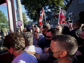 Gravel is thrown, top right, at Liberal Leader Justin Trudeau, left, who is surrounded by RCMP officers, at a protest during a campaign stop in London, Ontario.