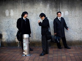 Men smoke cigarettes at a designated outdoor smoking area in Tokyo, Japan, in 2017.