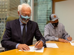 B.C. Indigenous Relations Minister Minister Murray Rankin, left, and Chief Marvin Yahey sign an agreement after the B.C. Supreme Court ruled earlier this year that the treaty rights of the Blueberry River First Nations had been violated.