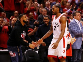 Kawhi Leonard of the Toronto Raptors high fives rapper Drake during game four of the NBA Eastern Conference Finals between the Milwaukee Bucks and the Toronto Raptors on May 21, 2019.