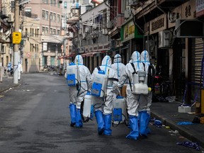 Health workers in protective gear prepare to spray disinfectant in a blocked off area in Shanghai's Huangpu district on Jan. 27, 2021, after residents were evacuated following the detection of a few cases of COVID-19 coronavirus in the neighbourhood.