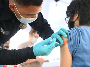 In this file photo Brandon Rivera, a Los Angeles County emergency medical technician, gives a second does of Pfizer-BioNTech Covid-19 vaccine to Aaron Delgado, 16, at a pop up vaccine clinic in the Arleta neighborhood of Los Angeles, California, August 23, 2021.