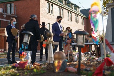 In this photo provided by the Office of the Prime Minister of Canada, Canadian Prime Minister Justin Trudeau (R) and Minister of Indigenous Services of Canada Marc Miller (L) lay flowers at a memorial outside of the Kamloops Indian Residential School in Kamloops, B.C., on Oct. 18, 2021.