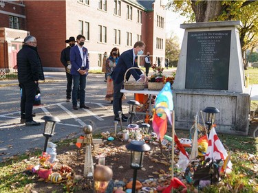 In this photo provided by the Office of the Prime Minister of Canada, Canadian Prime Minister Justin Trudeau (C) and Minister of Indigenous Services of Canada Marc Miller (R) lay flowers at a memorial outside of the Kamloops Indian Residential School in Kamloops, B.C., on Oct. 18, 2021.