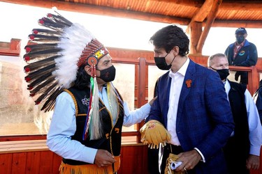 Canada's Prime Minister Justin Trudeau is offered a gift from Chief Michael LeBourdais at the Tk'emlups PowWow Arbour in B.C., Oct. 18, 2021.