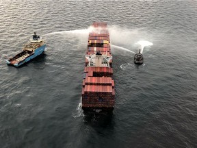 Tugboats pour water on the container ship Zim Kingston after it caught fire the day before off the coast of Victoria, British Columbia, Canada October 24, 2021.