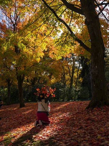 A woman throws up leaves while posing for a picture in Burnaby, Oct., 10, 2021.