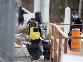 An asylum seeker crosses the border from New York into Canada followed by a RCMP officer at Roxham Road in Hemmingford, Que., March 18, 2020.