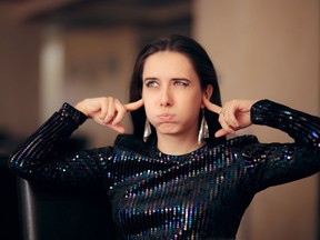 A woman plugs her ears trying to block loud noise.