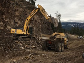 On Highway 8, drilling continues in preparation for blasting as part of flood recovery efforts. The excavator is pulling rock off the face of the bluff for it to be trucked out.