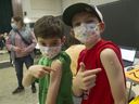 Ari Rosenzweig, 8, (left) and his brother Josh, 11, show off their Band-Aids at the Italian Cultural Centre in Vancouver on Nov. 29 after receiving their COVID-19 vaccines.