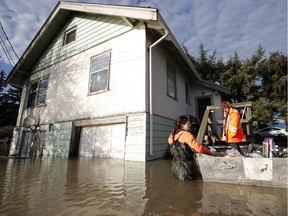 Nakita Penner (L) and her sister Brenna Penner (R) load personal items into a boat from their parents flooded home on November 21, 2021 in Abbotsford, British Columbia.