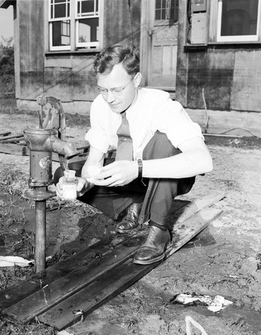 1948 Fraser River Flood - Chilliwack - An official collects a water sample from a residential water pump. 1948. Vancouver Sun.