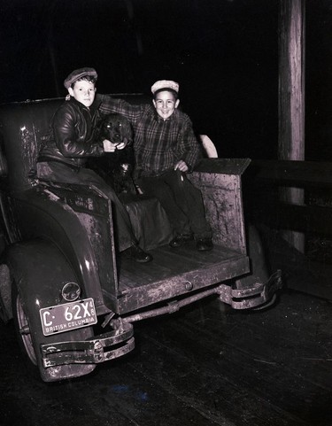 1948 Fraser River Flood - Nicomen Island & Deroche - Two boy hold a dog and smile from the back of a truck. 1948. Vancouver Sun.