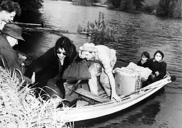 1948 Fraser River Flood - Nicomen Island & Deroche - Men help a woman out of a rowboat, where two young girls sit. 1948. Vancouver Sun.