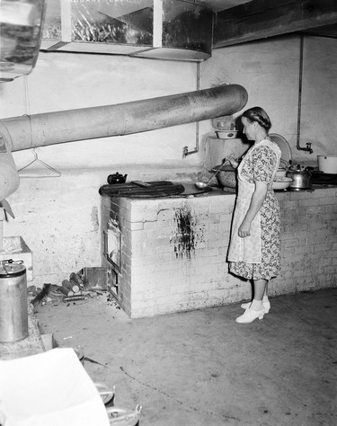 1948 Fraser River Flood - Sumas - Yarrows - A woman prepares food in a brick oven. 1948. Vancouver Sun.