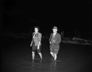 1948 Fraser River Flood - Sumas - Yarrows - A bouquet-wielding man and a woman wade through ankle-deep water at night. 1948. Vancouver Sun