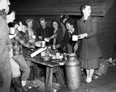 1948 Fraser River Flood - Vedder Canal - Men and women gather outside around a table as food is served. 1948. Vancouver Sun.