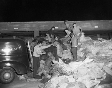 1948 Fraser River Flood - Vedder Canal - People work at night to unload piles of bags to be filled with sand. 1948. Vancouver Sun. (48/1179) [PNG Merlin Archive]