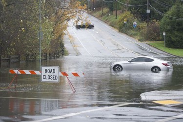 A car sits in a pool of water in the closed intersection of Old Yale Road and Mitchell Street in Abbotsford on Nov. 15, 2021.
