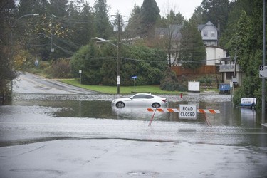A car sits in a pool of water in the closed intersection of Old Yale Road and Mitchell Street in Abbotsford on Nov. 15, 2021. Two days of rains have flooded, closed or washed out many roads in the Lower Mainland and the Fraser Valley.