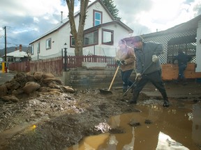 Residents clear thick mud outside a house a day after severe rain flooded the southern interior town of Princeton, Nov. 16, 2021.