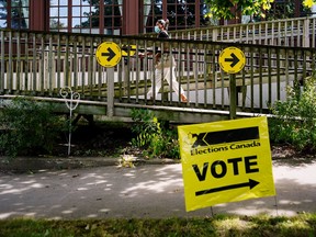 A woman walks by an Elections Canada sign at a polling station during in Canada's federal election, in Toronto Sept. 20, 2021.