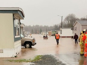 Emergency services workers help people evacuate as residents row a boat across a flooded area in Antigonish, Nova Scotia, Canada November 23, 2021 in this still image taken from social media video. Content shot November 23, 2021. Sean Cameron via REUTERS