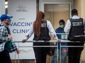 Security personnel and pedestrians wearing masks outside of a Covid 19 vaccine clinic in Toronto on Oct. 13th, 2021. Peter J Thompson/National Post