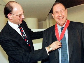 Jean Pierson (R), then managing director of Airbus Industries laughs as His Excellency Sir Michael Jay (L), the British ambassador to France adjusts the insignia of Commander of the Orderof the British Empire, February 18.