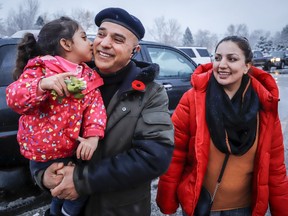 Evacuated residents from Merritt, B.C., Barkad Khan, centre, holds his daughter Mahira Khan, 4, as his wife Afreen Khan, looks on while they gather at a reception centre in Kamloops, B.C., Thursday, Nov. 18, 2021.