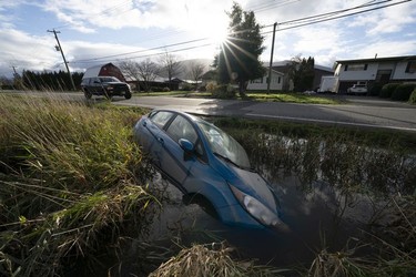 A car is seen in a flooded ditch along a road in Chilliwack, B.C., Tuesday, November 16, 2021.