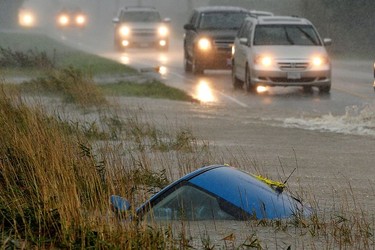 A car lies submerged in a ditch on a flooded stretch of road in Chilliwack after rainstorms lashed southern B.C., triggering landslides and floods, shutting highways, Nov. 15, 2021.
