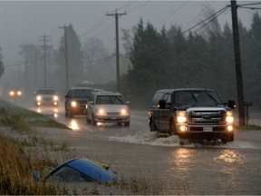 A car sits in a ditch on a flooded stretch of road after rainstorms in B.C. on November 15, 2021.  Recently, the risk of flooding has dropped in British Columbia's southern Interior while rising in the province's north, thanks to changing weather conditions.