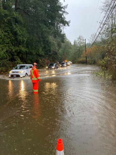 Emergency services personnel wade through floodwaters along a damaged road in Malahat, British Columbia.
