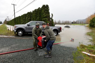 Darryl Jansen and Jared Emery pump water away from a building after rainstorms lashed the western Canadian province of British Columbia, triggering landslides and floods, shutting highways, in Chilliwack.