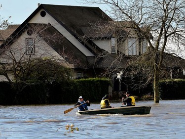 Three men paddle on a flooded road after rainstorms caused flooding and landslides in Abbotsford, British Columbia, Canada November 16, 2021.