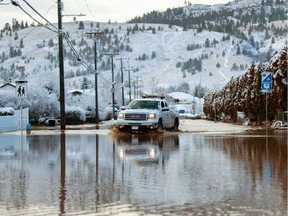 A utility vehicle drives through a flooded street a day after severe rain prompted the evacuation of the city of 7,000 in Merritt.